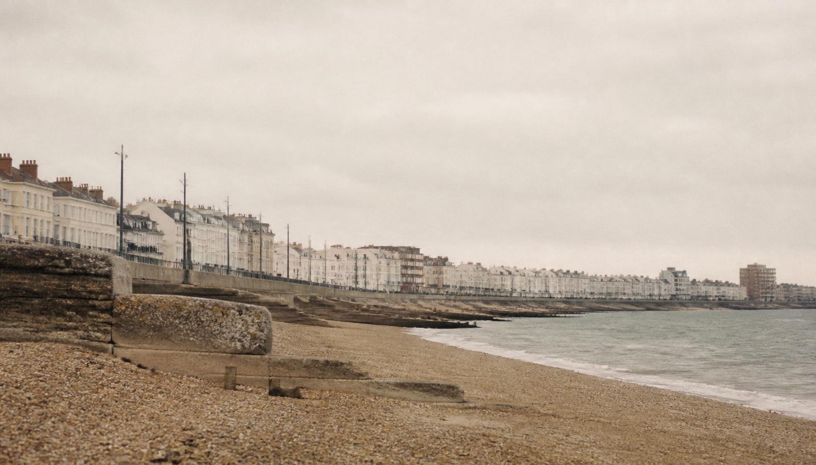 Southsea seafront in Portsmouth on an overcast morning, shingle beach and pale terraces
